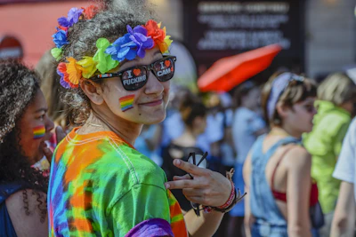A joyful group of friends wearing rainbow-themed accessories and smiling.