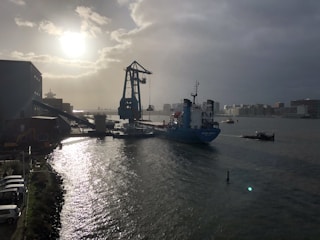 A cargo ship loaded with crates of machinery leaving an Egyptian port at sunset.