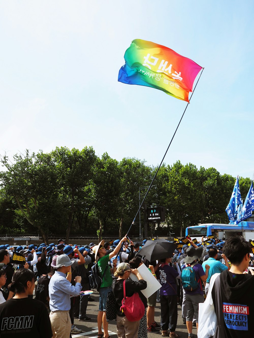 man in green shirt holding out banner with Hangul script surrounded by people during daytime