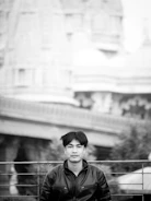 Black and white image of a leather jacket draped over a modern chair in a bright room.