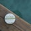 A round container of hemp whipped body butter is placed on a wooden surface. The label highlights that it contains organic certified ingredients and promotes its properties such as being an antioxidant and skin conditioner. The background features a calming, blurred teal color.