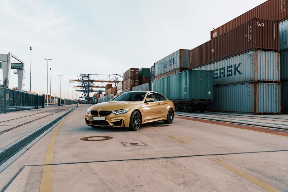 yellow BMW sedan parked near containers during daytime