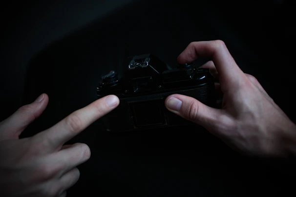 An intimate close-up of hands gently holding a vintage camera, bathed in soft white light.