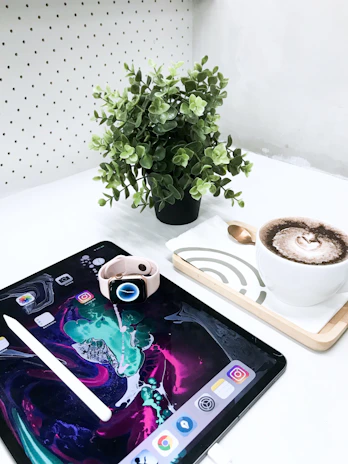 Brightly colored digital art prints displayed on a tablet with a cup of coffee nearby.