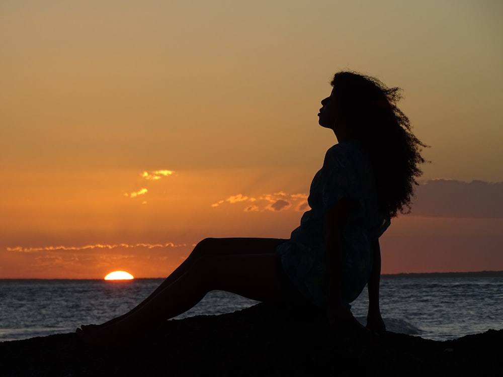silhouette of a woman sitting on the ground during golden hour