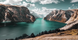 body of water between brown mountains