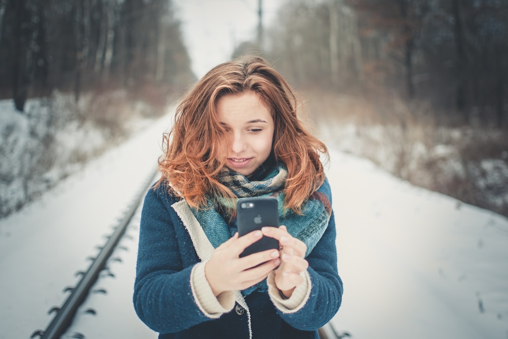 mulher segurando o telefone em pé na trilha