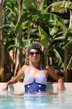 woman leaning on concrete near banana trees