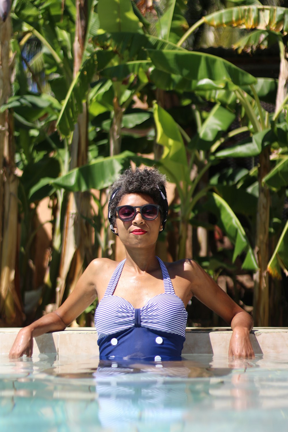 woman leaning on concrete near banana trees