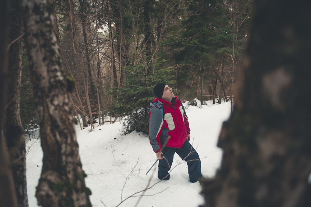 昼間、木のそばの雪の上を歩く男性
