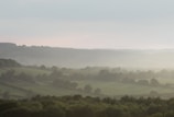A panoramic view of the finca with mist rolling over the hills and distant city lights.