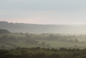 A panoramic view of the finca with mist rolling over the hills and distant city lights.