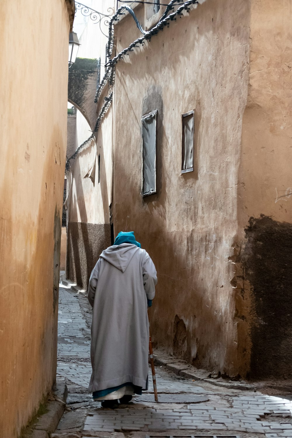 person wearing gray robe holding stick during daytime