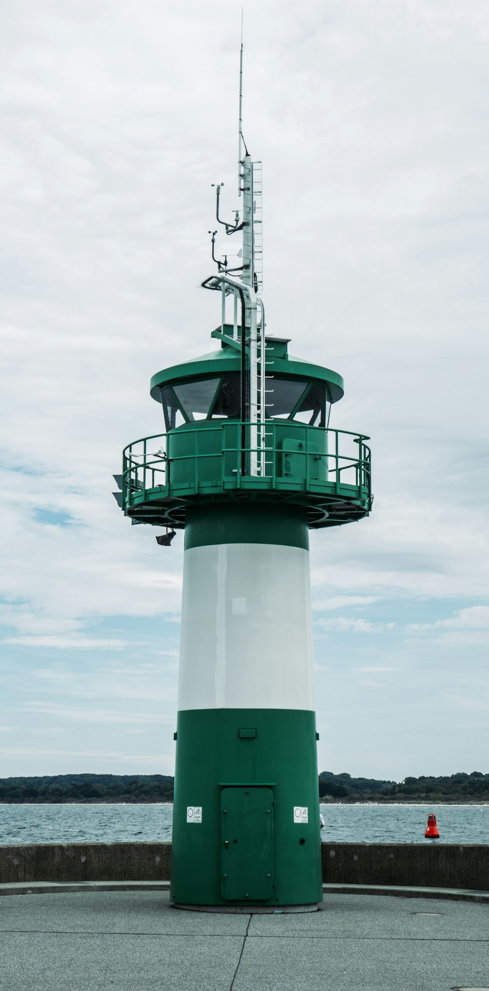 green and white lighthouse near body of water