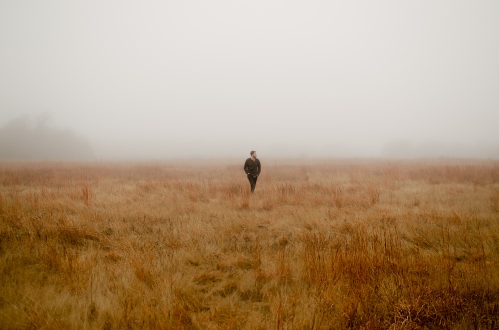 man walking surrounded by brown grass