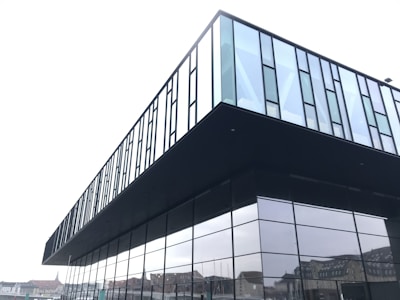 A modern commercial building with glass windows reflecting the city.