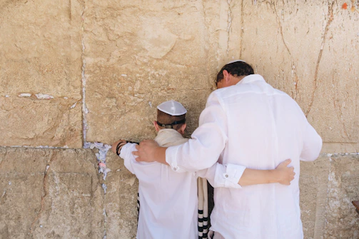 two men in white top standing beside wall