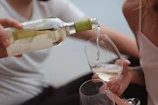 Close-up of hands gently pouring natural wine into a glass during an intimate tasting session.