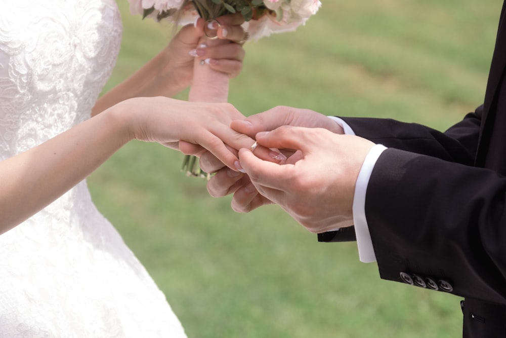 man putting wedding ring on bride during daytime