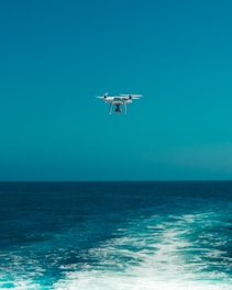 Drone flying over a scenic coastline with clear blue water.