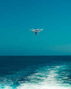 Drone flying over a scenic coastline with clear blue water.