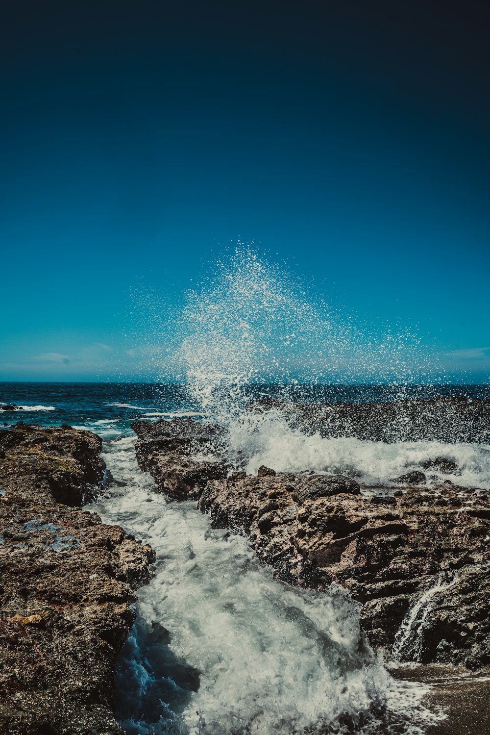 water splashing on rock under blue sky