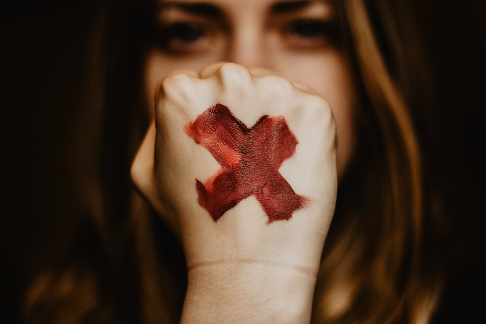 selective focus photography of woman showing her left hand with x painting