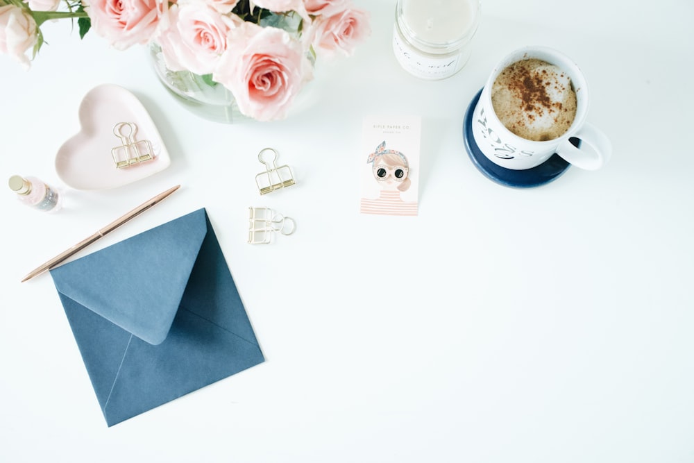 blue envelope and white ceramic mug on white table