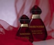 Luxurious perfume bottle with deep red and gold tones on black background