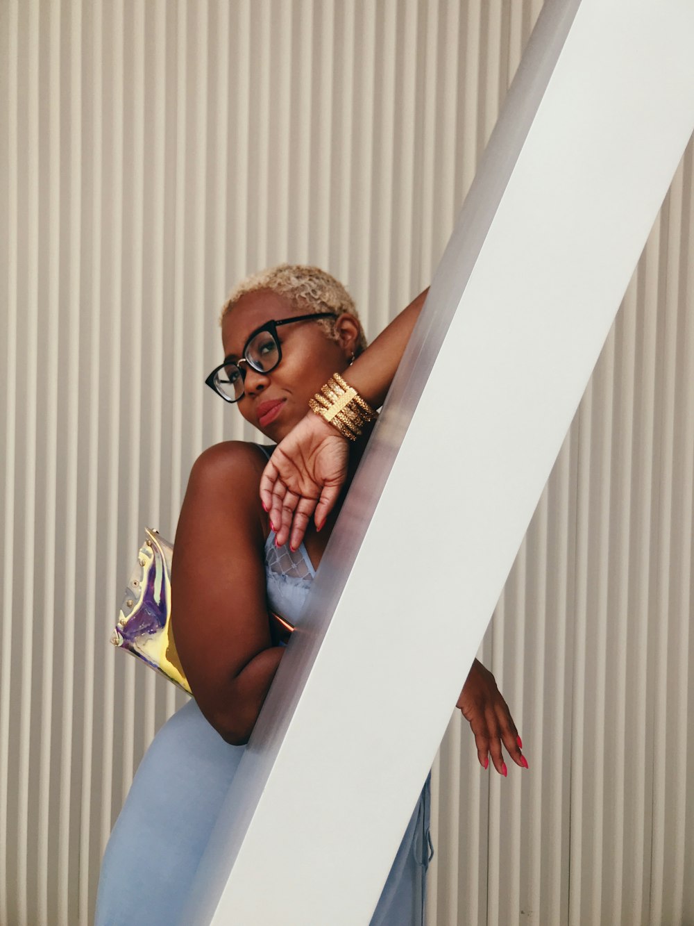 woman in eyeglasses leaning on white post