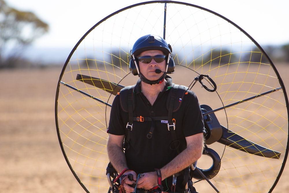 man in black polo shirt wearing black headset and blue helmet standing outdoor