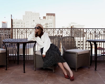 A woman lounging in a chic outfit on a modern terrace at sunset.