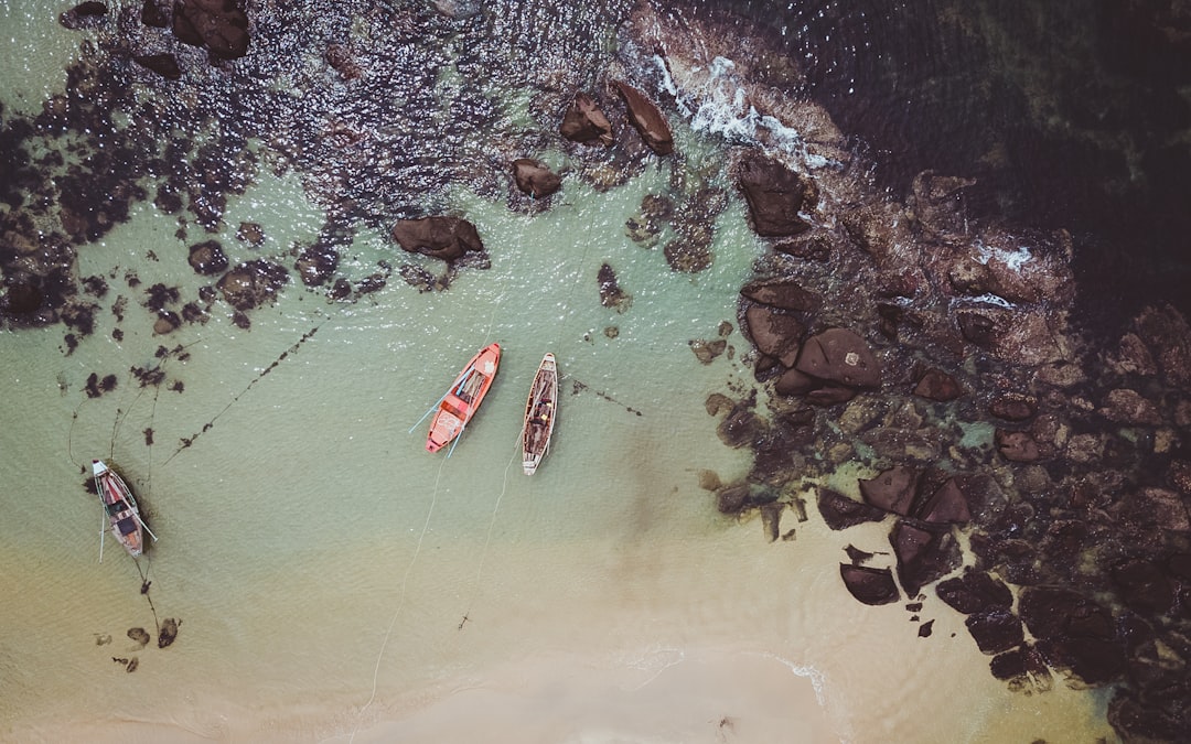 aerial photography of three boats near rocky shore during daytime
