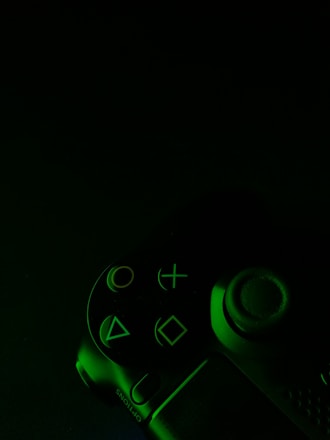 green and black game controller in dimmed light