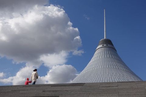 woman and child walking beside gray concrete building