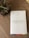 A hardcover book with a white cover is placed on a wooden surface. The book is titled 'Inside Apple's design process during the golden age of Steve Jobs' by Ken Kocienda. The cover features minimalist icons and a colorful strip at the bottom. Next to the book, there is a plant in a wicker basket.