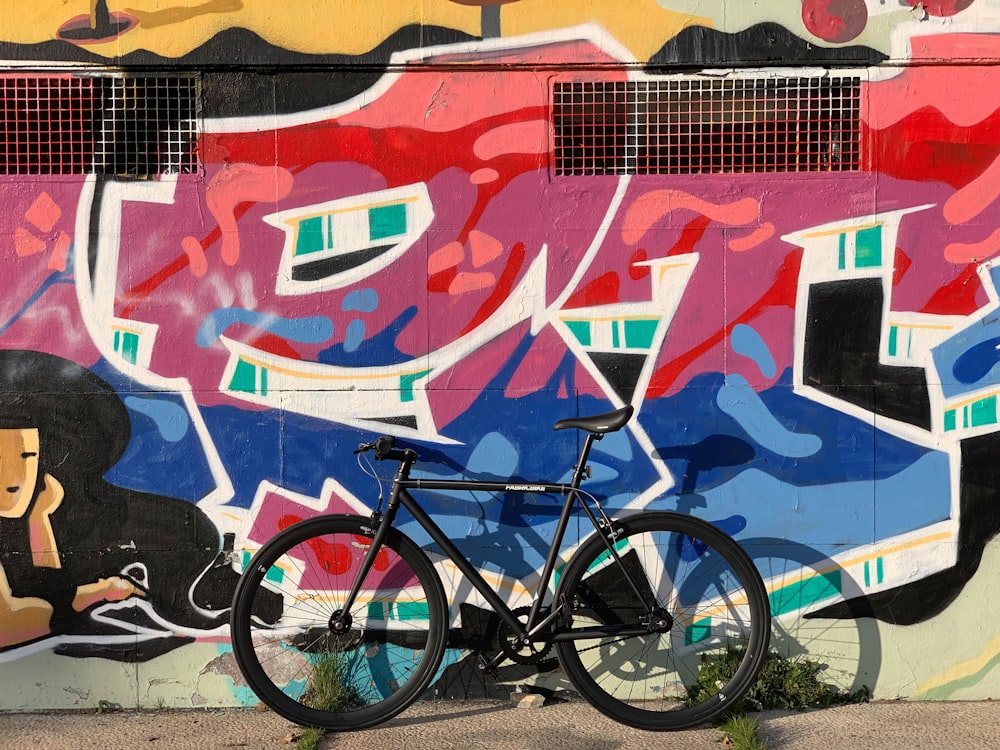 black road bike near concrete fence with graffiti design