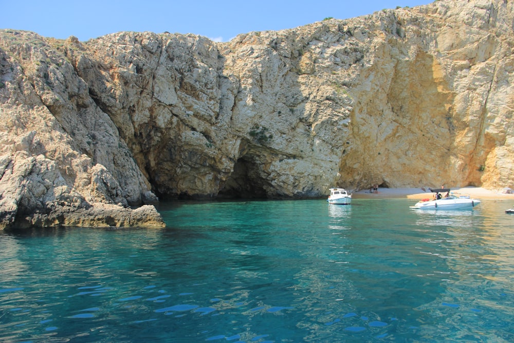 raft and speedboat on sea near rock mountain