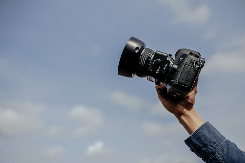 man using his black DSLR camera