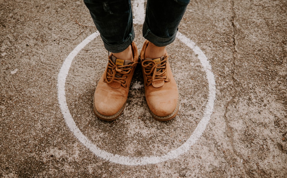 Person mit Lederschuhen, die mit Kreis auf dem Boden steht