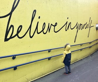 toddler looking at believe in yourself graffiti