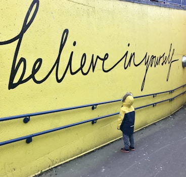 toddler looking at believe in yourself graffiti