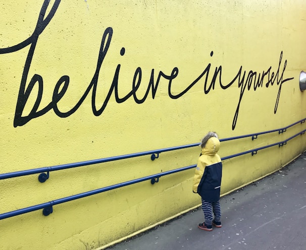 toddler looking at believe in yourself graffiti