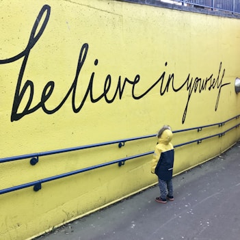 toddler looking at believe in yourself graffiti