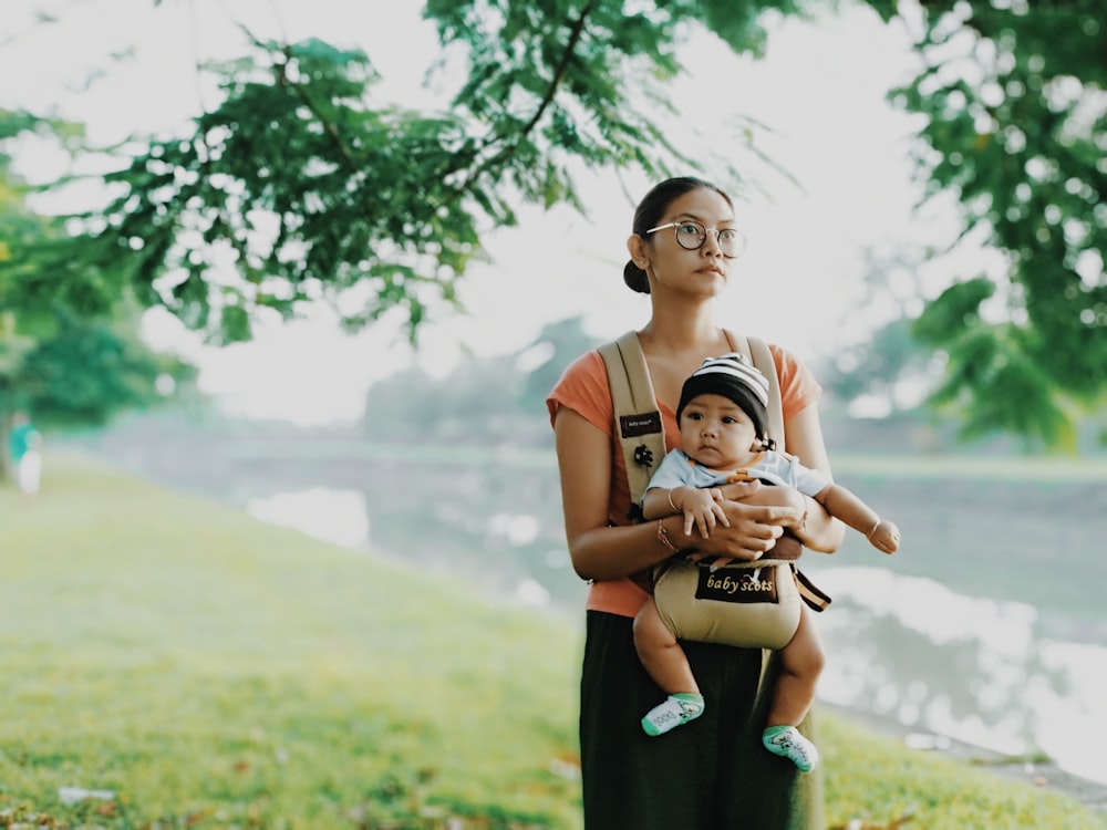 woman carrying his child standing near river