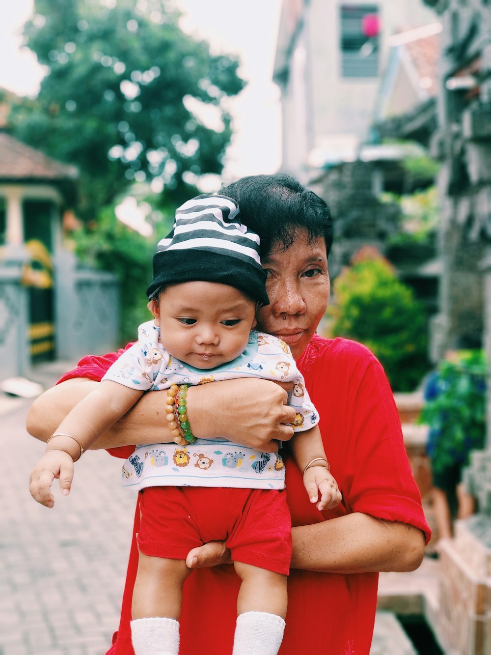 woman carrying a baby near houses at daytime