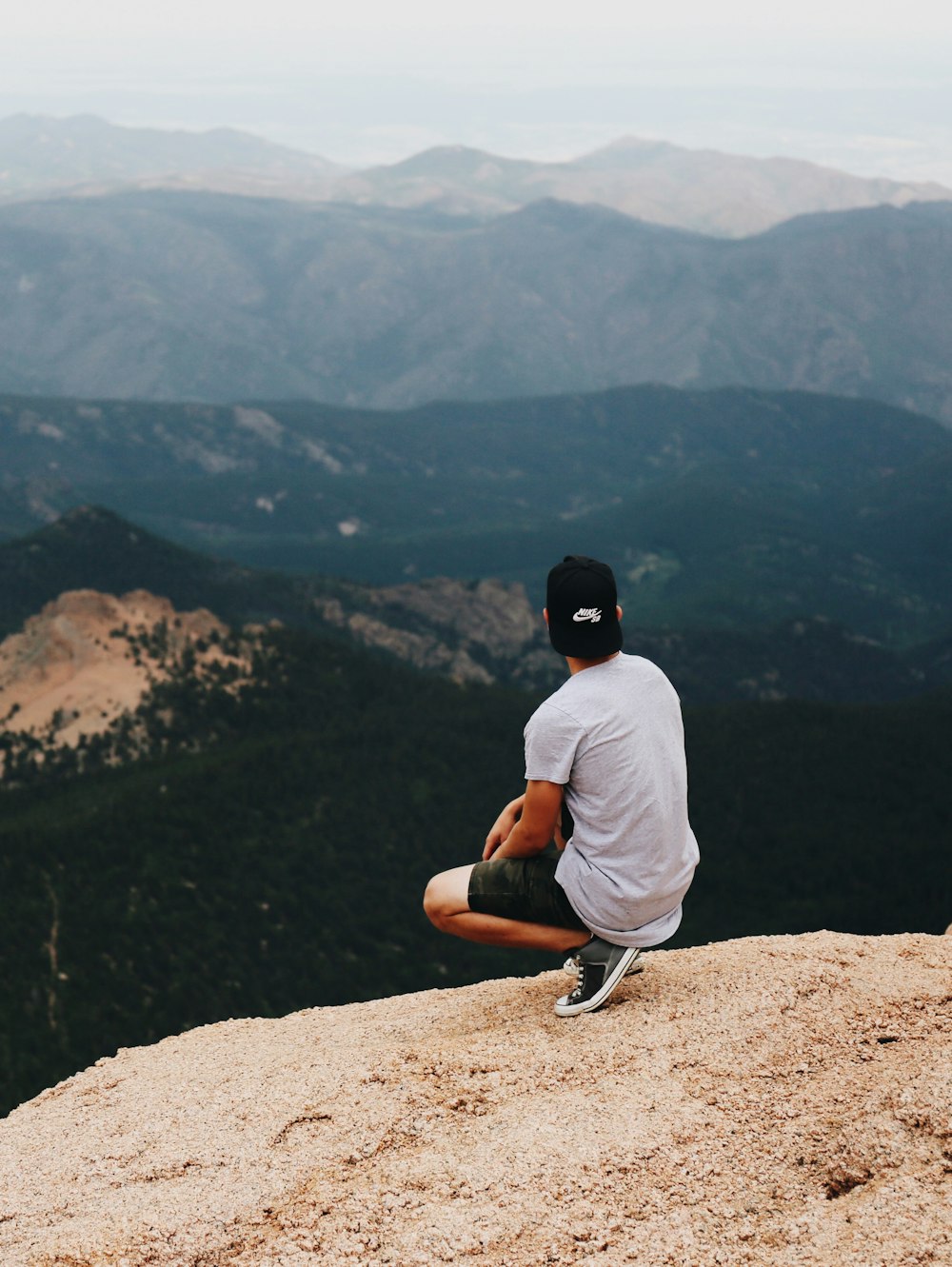 sitting person looking the mountain during daytimee