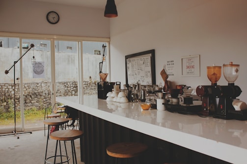 A neatly arranged coffee counter with earth-toned accessories and natural light streaming in.