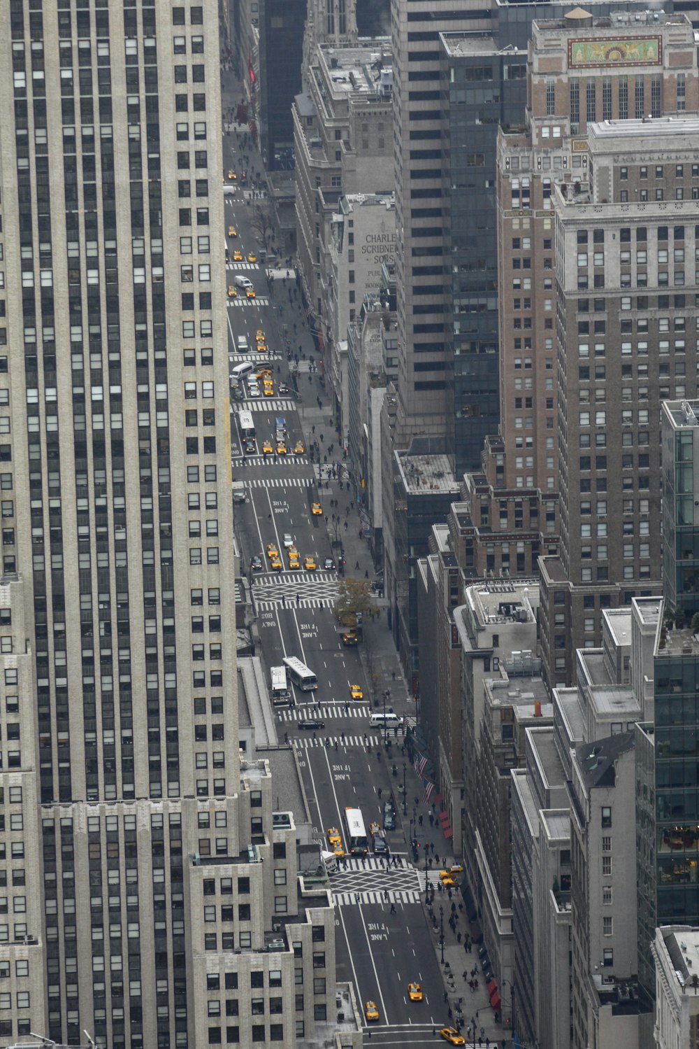 aerial photography of vehicle passing on road between concrete high-rise buildings during daytime