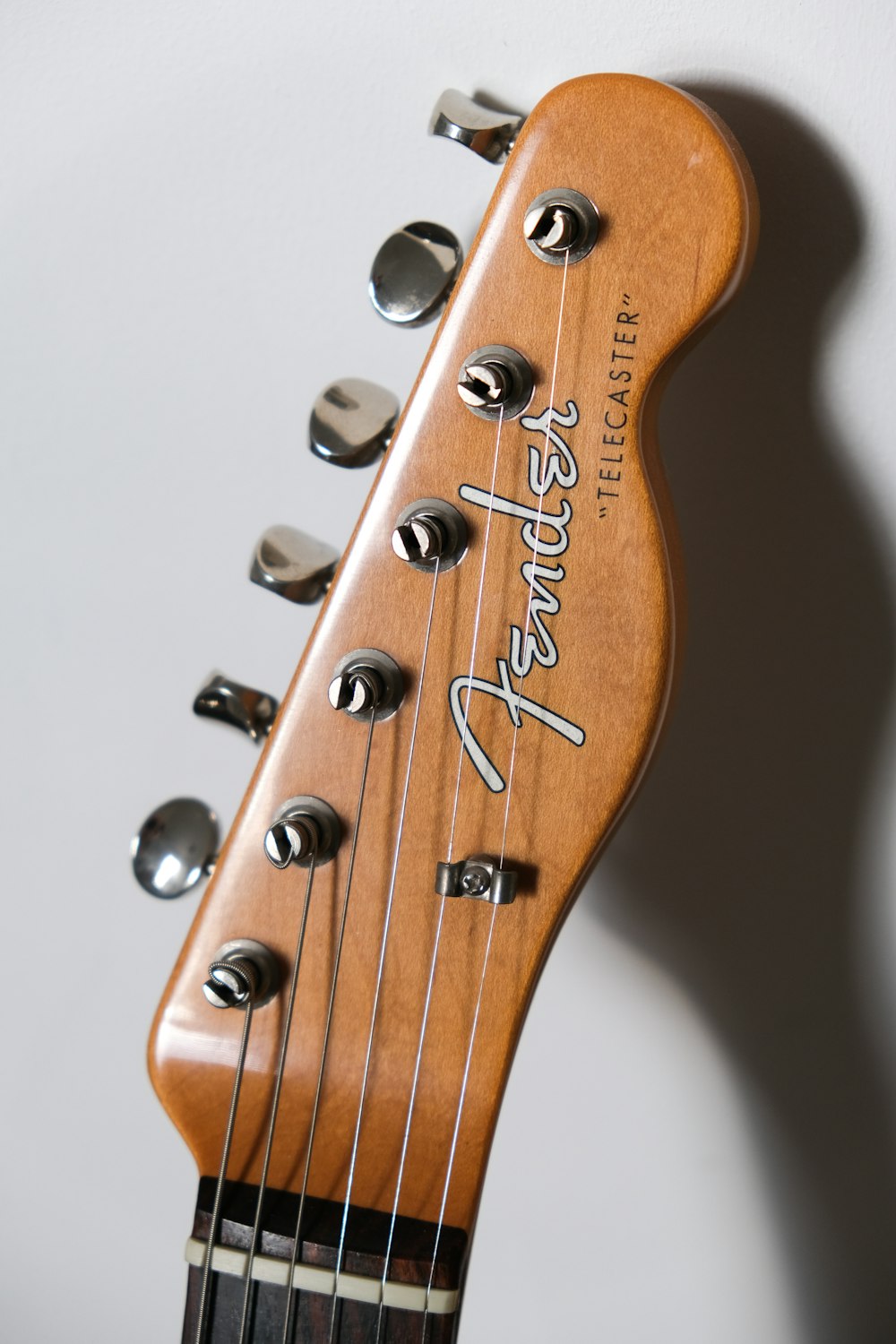 brown Fender guitar headstock on white surface